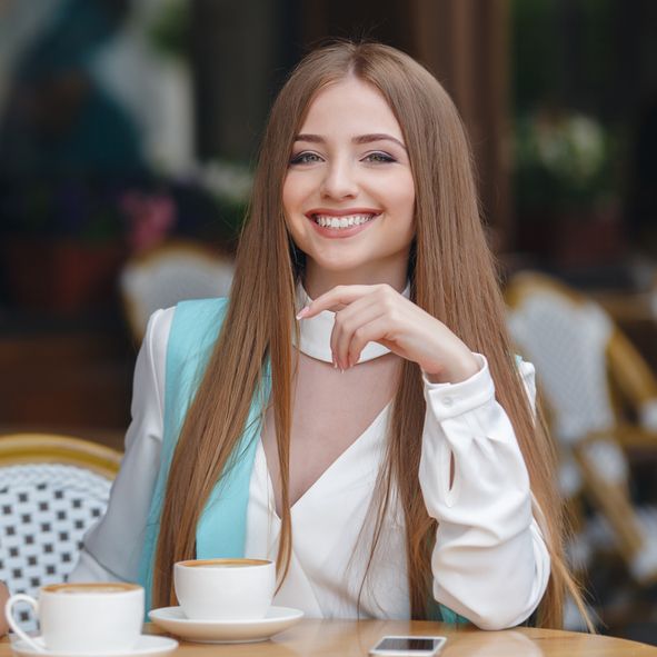 A woman holding a jar of cream in front of her face.