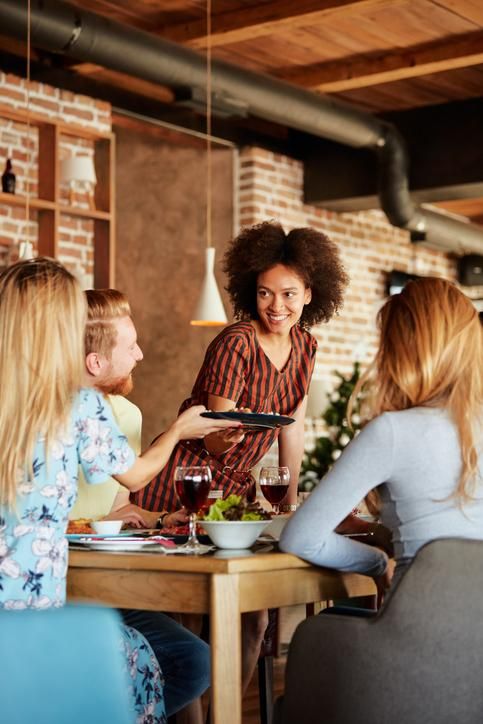 A woman in a black coat is waiting for a train.